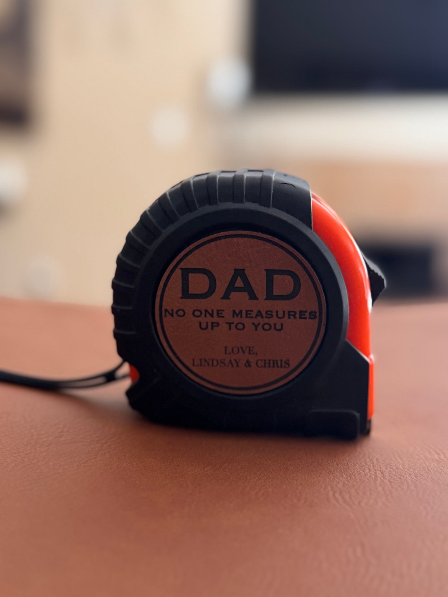 Tape measure with 'DAD' text on a wooden surface
