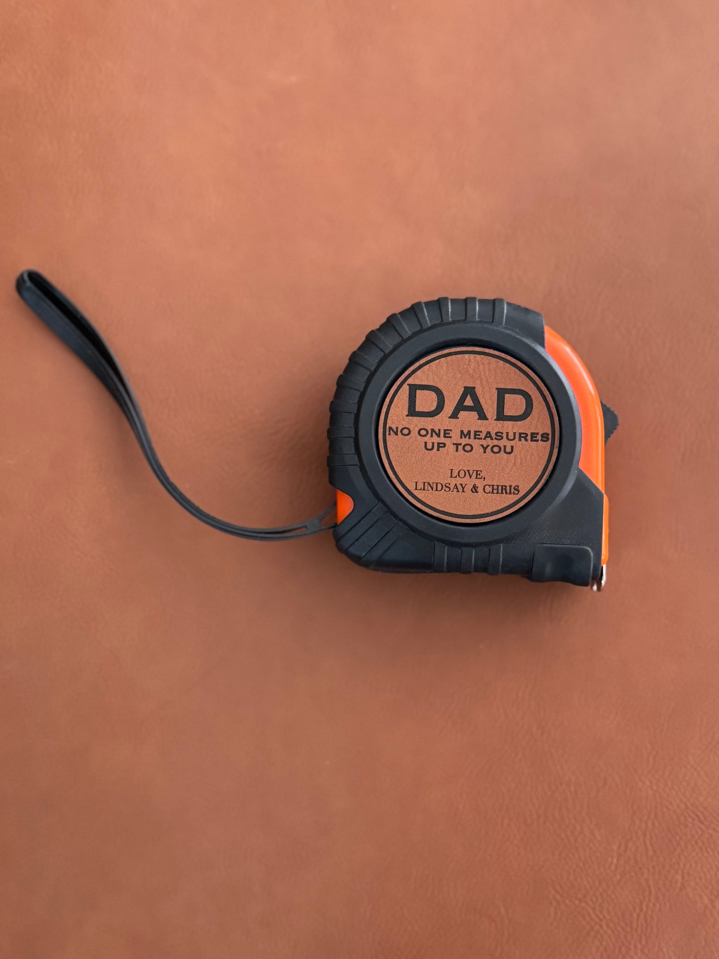 Tape measure with 'DAD' engraving on a brown leather background