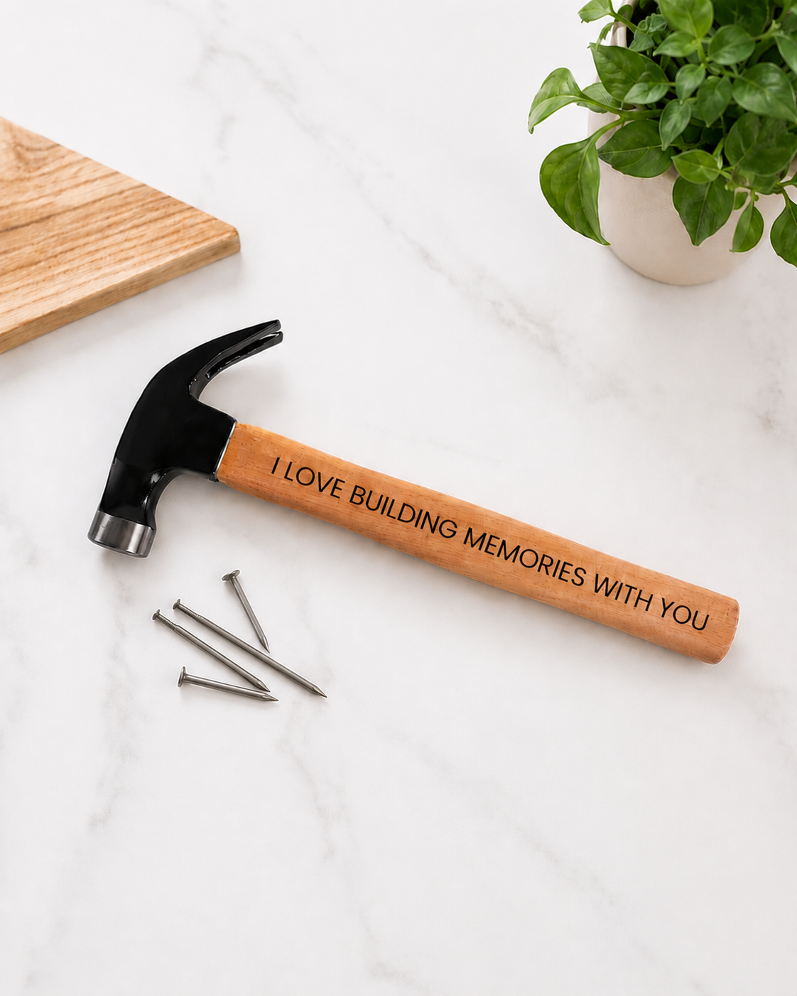 Hammer with engraved message on a white surface with a plant in the background